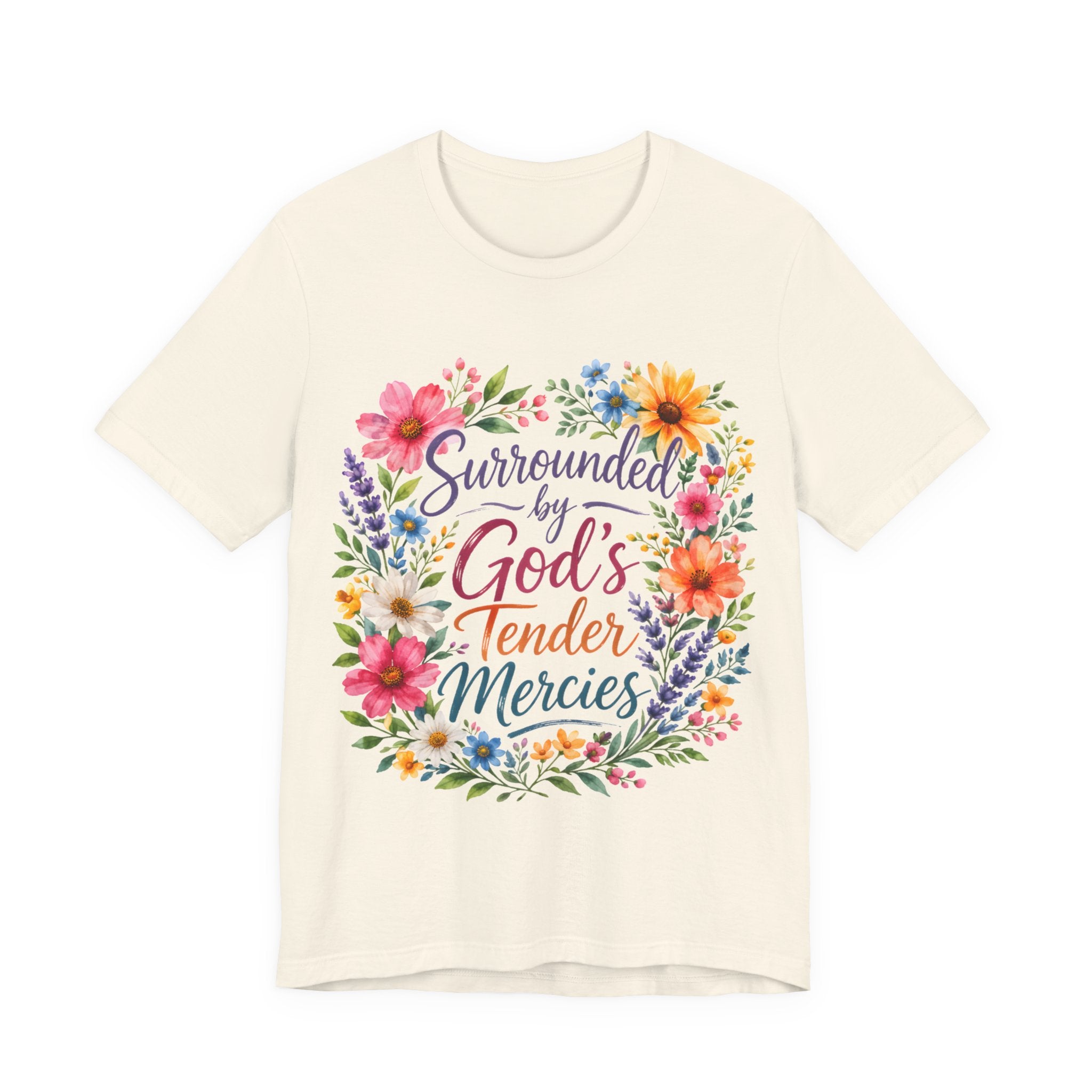 Natural t-shirt with colorful floral design and text 'Surrounded by God's Tender Mercies' on a white background