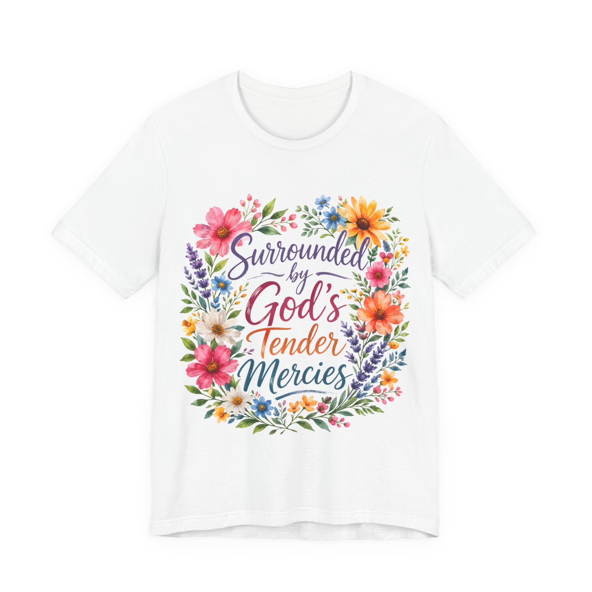 White t-shirt with colorful floral design and text 'Surrounded by God's Tender Mercies' on a white background