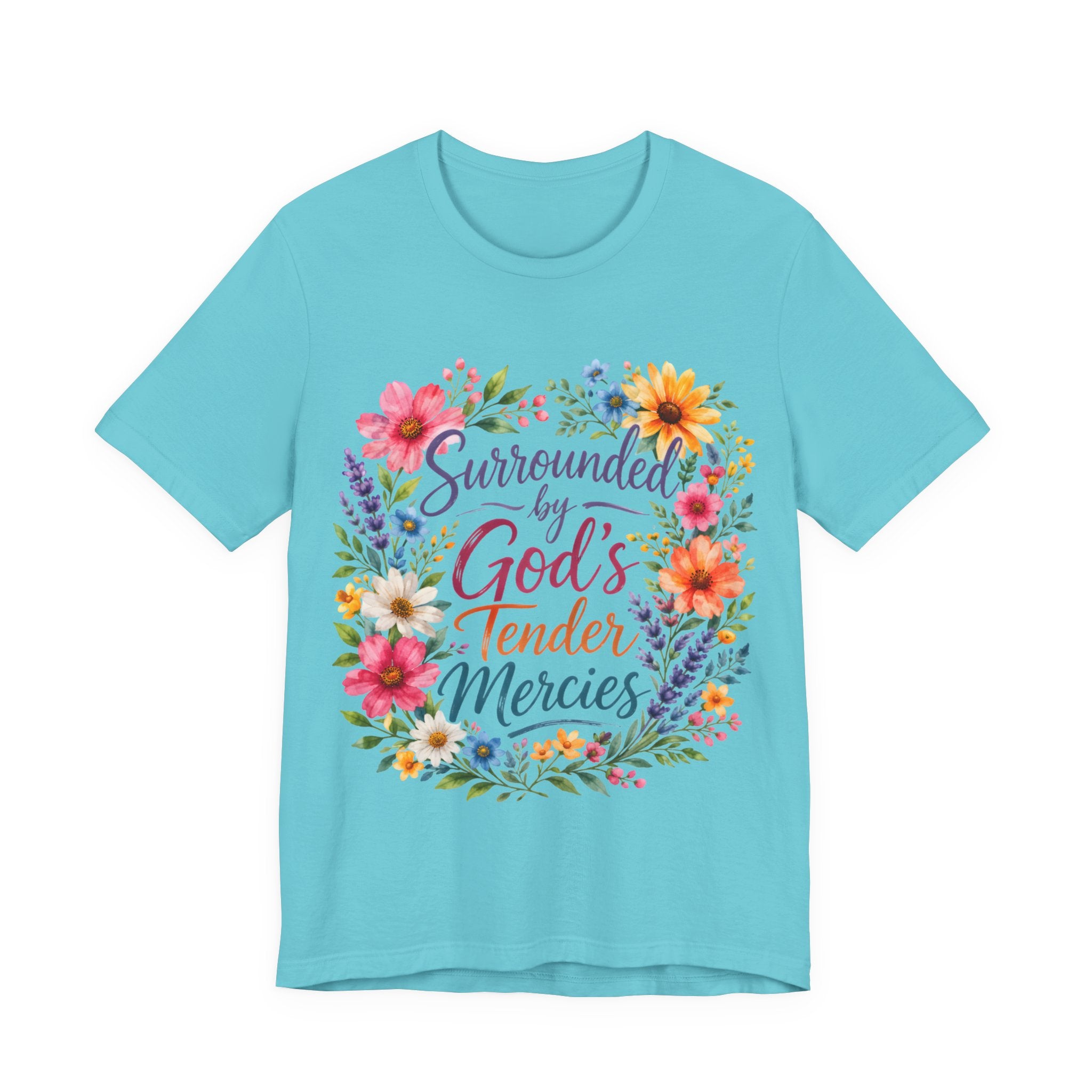 Turquoise t-shirt with colorful floral design and text 'Surrounded by God's Tender Mercies' on a white background